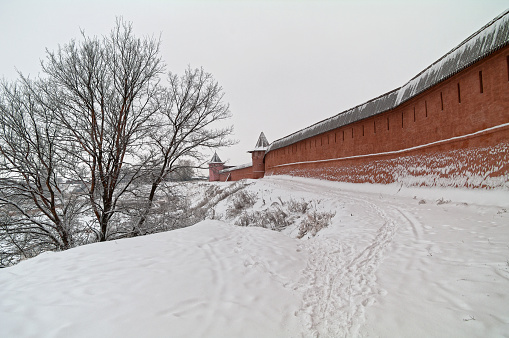 The defensive wall of the Saviour Monastery of Saint Euthymius on the high bank of the Kamenka River. Suzdal, Russia, cloud day in December.