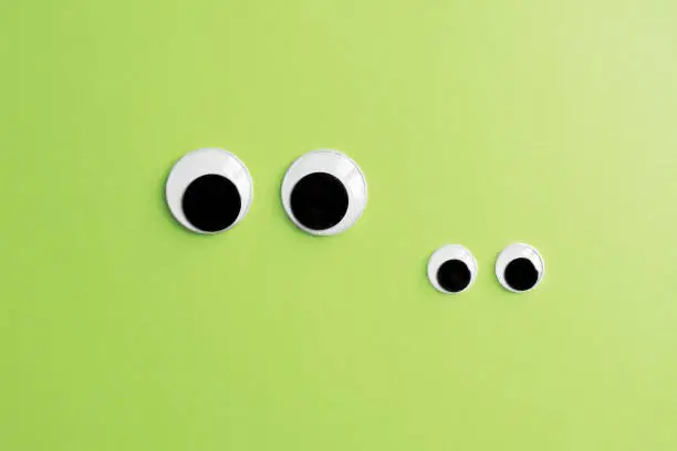 Photo of invisible frog googly eyes on green color background