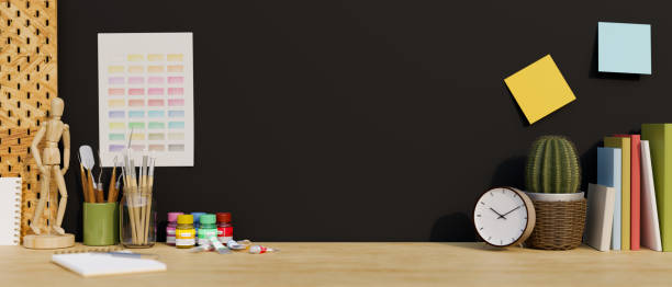 istock Wooden tabletop with copy space, painting tools, and decor over black wall background. 1400782985