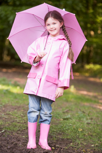 Young girl outdoors with umbrella wearing waterproof smiling