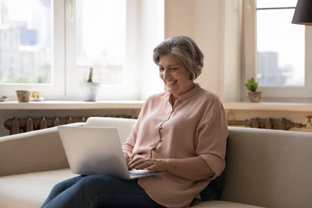 istock Happy middle aged woman sit on sofa using laptop 1400788398