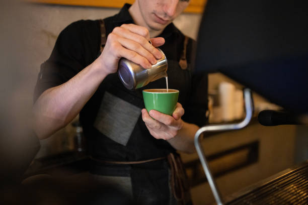Caucasian male barista making coffee while using espresso maker, at the coffee shop