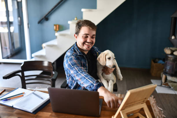 istock Male Freelancer Smiling While Keeping Dog Close By And Working From Home 1400789625