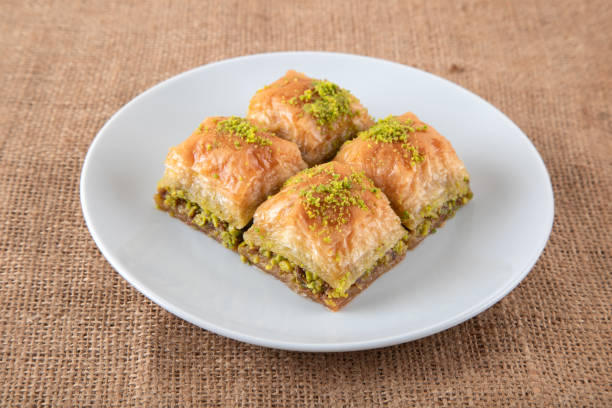 baklava al pistacchio su un piatto bianco. primo piano di quattro fette di baklava - baklawa foto e immagini stock