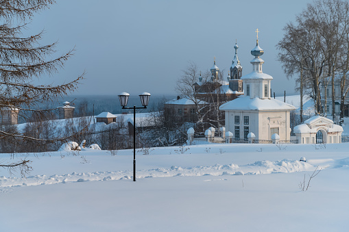 Panoramic view of the ancient city of Cherdyn (Northern Ural Russia), located on several hills. Historic center with beautiful wooden churches, houses, trees and deep snow on a winter day