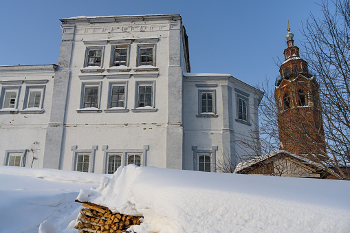 Ancient architecture of Cherdyn (Northern Ural Russia) - cities on 3 hills in winter. Tall brick tower with golden domes and bells, light historic house with a rasp of firewood and a lot of white snow