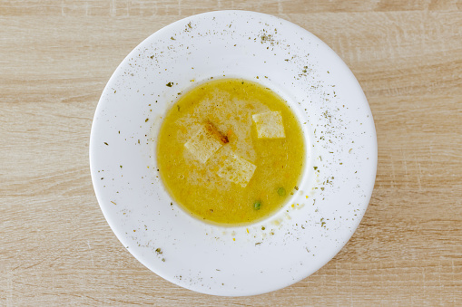 Chicken soup in white plate on wooden table