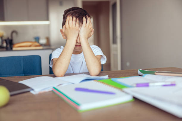 istock Caucasian sad little schoolboy closing face with hands and crying at homework. 1400794181