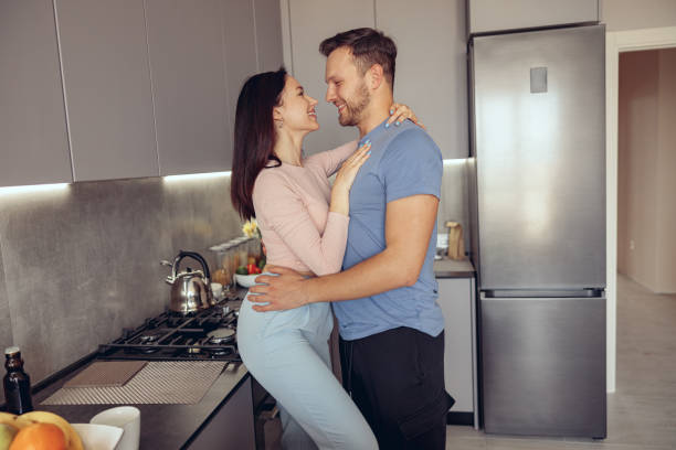 Young Caucasian just-married couple in kitchen of new home. Wife and husband hugging. Young Caucasian just-married couple in kitchen of new home. Wife and husband hugging. In love. trophy wife stock pictures, royalty-free photos & images