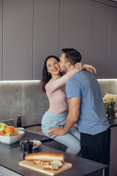 Caucasian handsome man kissing beauiful woman ,couple standing in kitchen in morning. Caucasian handsome man kissing beauiful woman ,couple standing in kitchen in morning. Vertical. trophy wife stock pictures, royalty-free photos & images