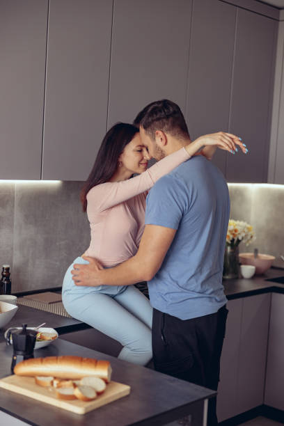 Portrait of couple in love embracing at home interior. man and woman hugging in kitchen. Portrait of couple in love embracing at home interior. man and woman hugging in kitchen. Vertical. trophy wife stock pictures, royalty-free photos & images