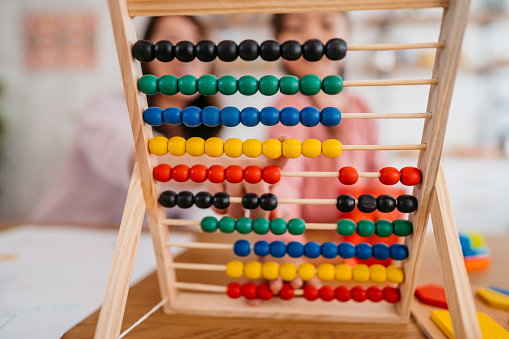Close-up of an abacus toy with mother and daughter in the background.
