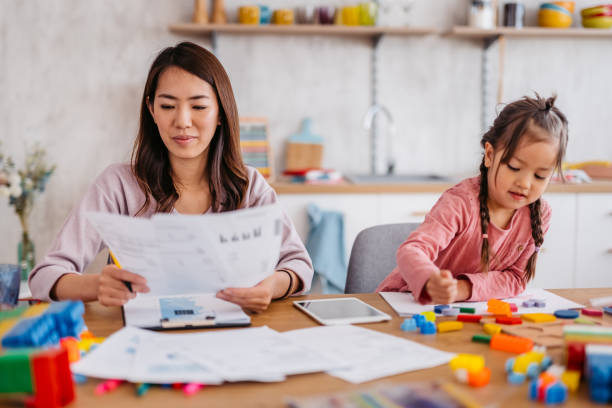 istock Young Mother Checking Her Finances While Her Daughter Is Playing Next To Her 1400795764