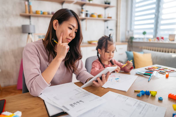 istock Young Mother Checking Her Finances While Her Daughter Is Playing Next To Her 1400795830