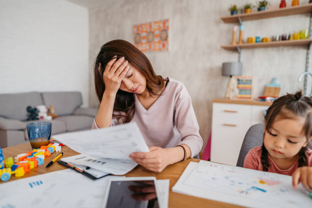 istock Young Mother Checking Her Finances While Her Daughter Is Playing Next To Her 1400795995