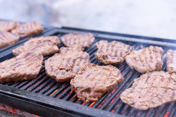 Grilling steaks on flaming grill and shot with selective focus