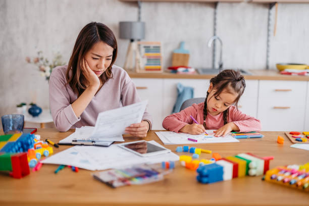 istock Young Mother Checking Her Finances While Her Daughter Is Playing Next To Her 1400796197