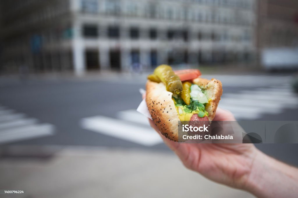 Hand holding hot dog on street Close-up of hand holding hot dog. Street food in Chicago."n Hot Dog Stock Photo