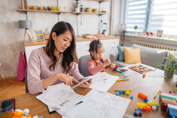 istock Young Mother Checking Her Finances While Her Daughter Is Playing Next To Her 1400796323