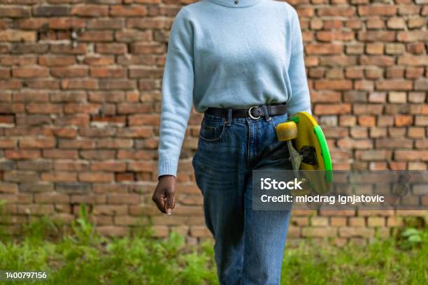 Unrecognizable woman Black ethnicity holding a longboard
