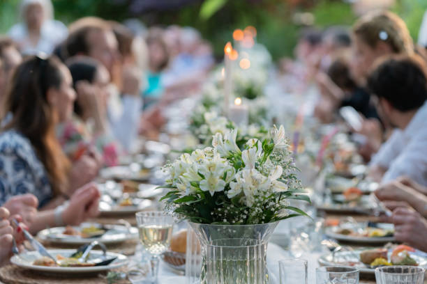 Group of people having dinner at wedding reception table at back yard.