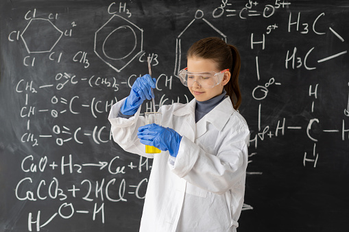 Little girl scientist examining flask with chemical reagent. Schoolgirl making experiment in chemistry class. children working in a chemistry lesson. Education concept
