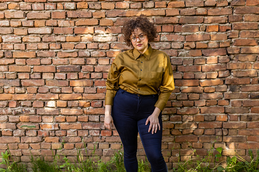 Portrait of young Caucasian body positive woman, in front of the brick wall