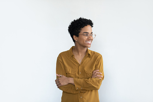 Happy confident young Black business woman professional head shot portrait. Female African business leader looking away with toothy smile, thinking, posing isolated at white background