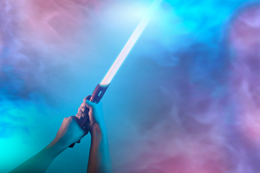 a fantastic laser sword lightsaber in the hands of a man