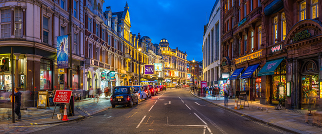 Traffic along Shaftesbury Avenue past the tourist crowds and the billboards of London’s vibrant theatre district at night.