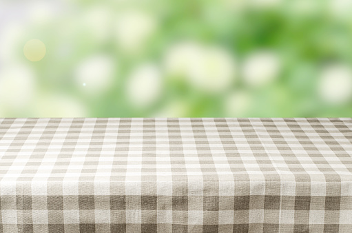 An empty table with a napkin. Blurry summer or spring background.