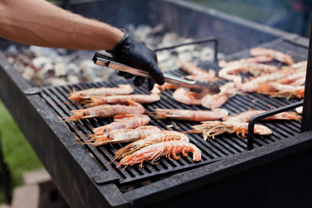 Cooking seafood shrimp on barbecue grill. Summer outdoors party concept, local food market concept