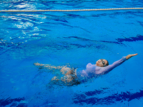 high angle chinese woman backstroke swimming with confidence