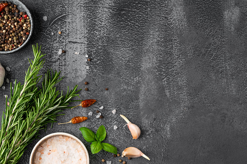 Dark stone cooking background. Spices, fresh basil, rosemary and garlic. Top view. Free space for your text