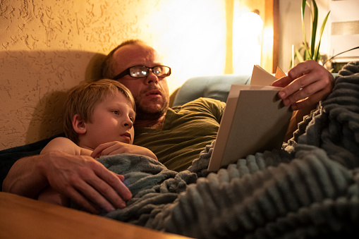 Father reading a book to son before going to bed