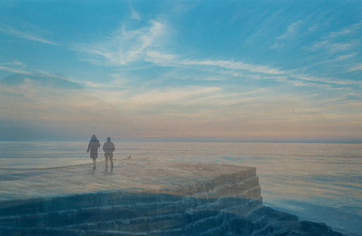 Two persons, in silhouette, walking on the Cobb  by Lyme Regis on a summer's evening, double exposure.