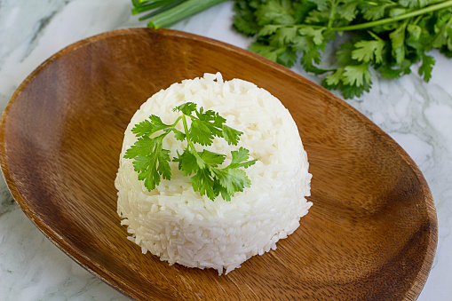 Cooked plain white rice (Jasmine rice) served in a wooden plate.