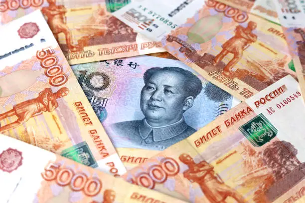 Photo of Chinese yuan banknote surrounded by russian rubles