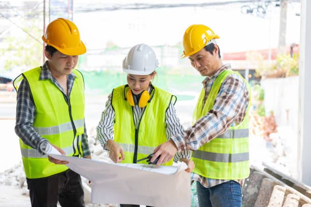 istock Asian engineer or Young Female Architect put on a helmet for safety and talk with a contractor on a construction building factory project, Concept of Teamwork, Leadership concept. 1400811253