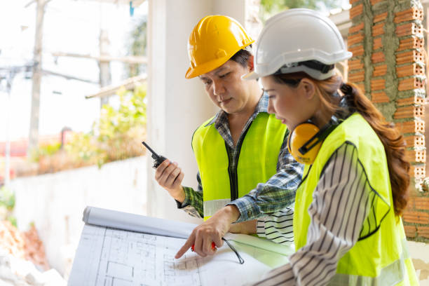 istock Asian engineer or Young Female Architect put on a helmet for safety and talk with a contractor on a construction building factory project, Concept of Teamwork, Leadership concept. 1400811287