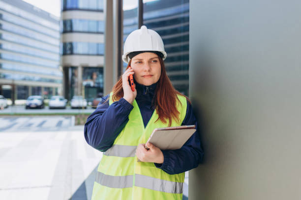 istock Serious young Architect woman talking over phone disappointed hear bad news, constructor wearing white helmet and safety yellow vest speaking having unpleasant smartphone conversation 1400813079