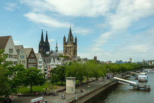 Cologne, Germany - May 17, 2022 : Panoramic view of the cathedral Saint Martin, the Dom and people walking next to the river Rhine of Cologne