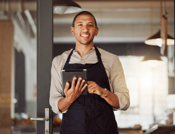 Portrait of businessman using a digital tablet. Mixed race business owner using a wireless digital device. Shop owner standing in entrance using an online app. businessman using a digital device retrato de un hombre de negocios usando una tableta digital. propietario de un negocio de raza mixta que utiliza un dispositivo digital inalámbrico. propietario de la tienda de pie en la entrada usando una aplicación en línea. hombre de negocios usando