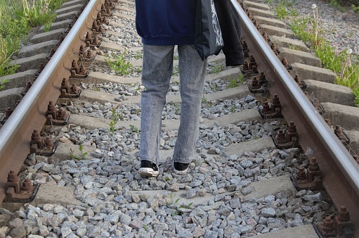a man walking on rails, a view of feet walking on railroad tracks. High quality photo