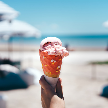 Strawberry ice cream cone at beach cafe outdoor on summer day.