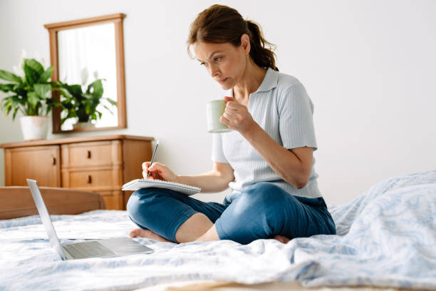 istock Ginger mature woman writing down notes while working with laptop at home 1400823225