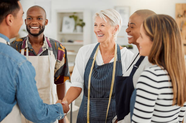 istock Group of happy diverse creative designers having a meeting while standing together at work. Cheerful colleagues greeting and shaking hands in an office. Male and female coworkers discussing a strategy 1400823472