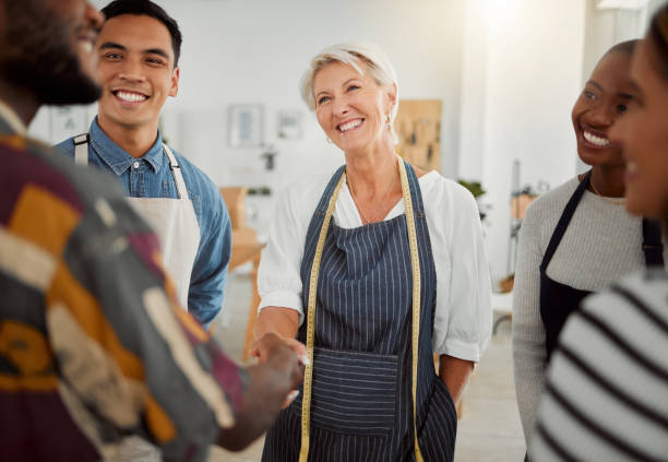 istock Group of happy diverse creative designers having a meeting while standing together at work. Coworkers greeting and shaking hands in an office. Male and female coworkers discussing a strategy 1400823474