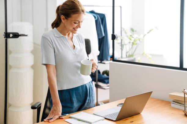 istock Ginger mature woman working with laptop while standing at desk 1400824927