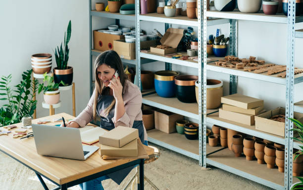 istock Happy Woman Potter In Talking On A Mobile Phone With Customer While Preparing Packages For Shipping At Her Store 1400826065